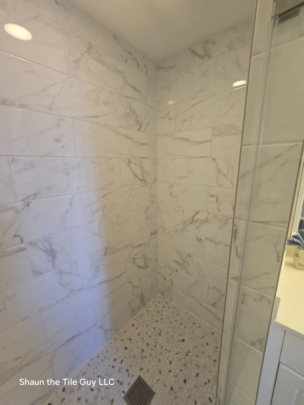 Same shower rebuilt in marble-look porcelain, finished and grouted