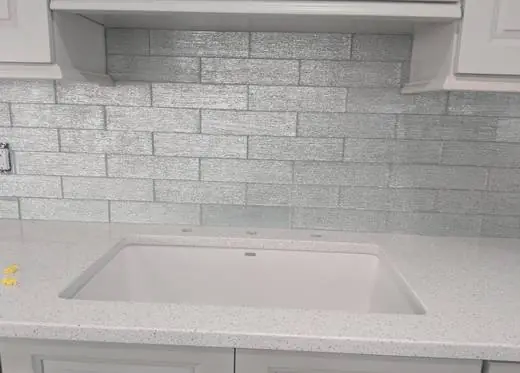 Metallic glass subway backsplash above a farmhouse sink