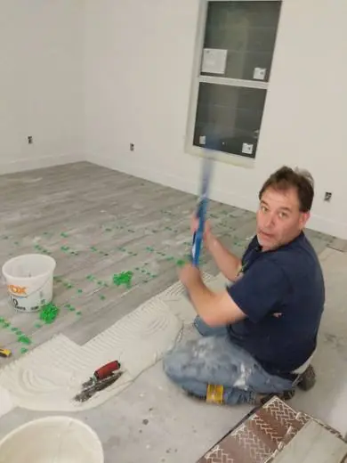 Shaun setting tile with a mallet
