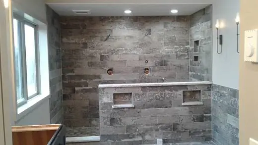Walk-in shower with stacked plank-look tile, niches and a built-in bench