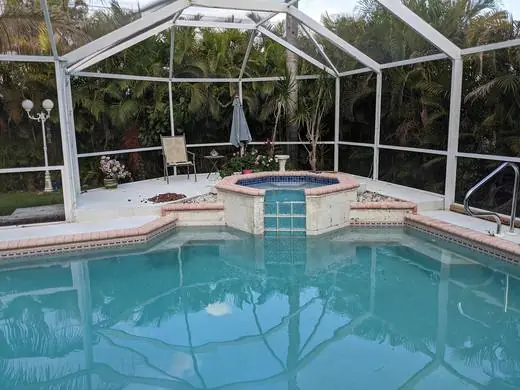 Pool spa with a blue waterline tile and brick coping