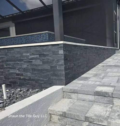 Stacked slate wall with a glass-mosaic cap beside the pool